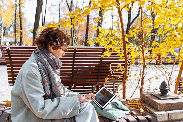 Happy teenage girl in autumn park on video call through laptop