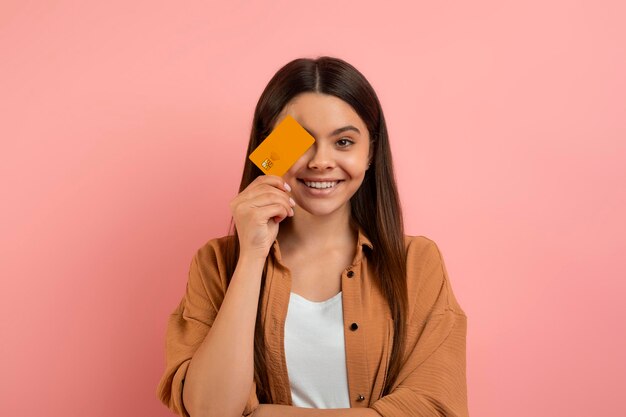 Foto adolescente felice che tiene la carta di credito e sorride alla macchina fotografica