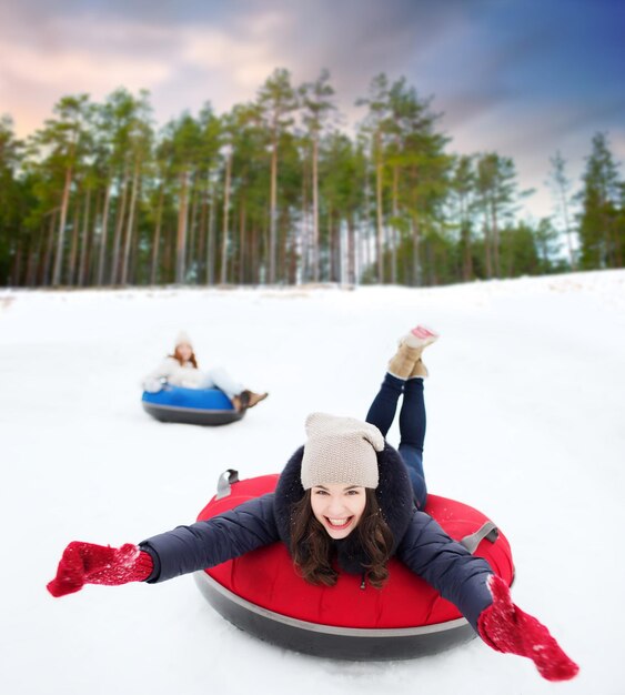 happy teenage girl sliding down hill on snow tube