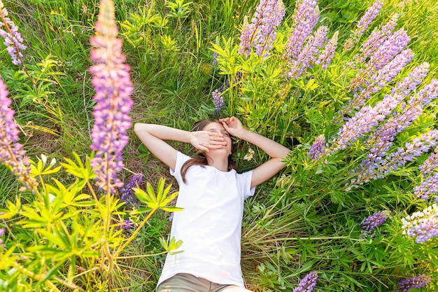 Happy teenage girl smiling outdoor beautiful young teen woman resting lying on summer field with blo