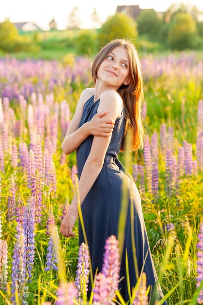 Happy teenage girl smiling outdoor. Beautiful young teen woman resting on summer field with blooming wild flowers green background. Free happy kid teenager girl, childhood concept