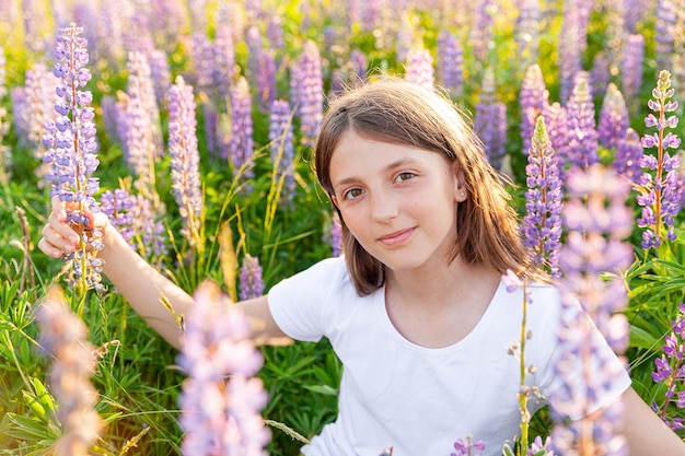 屋外で笑って幸せな10代の少女。咲く野生の花の緑の背景と夏のフィールドで休んでいる美しい若い10代の女性。無料の幸せな子供ティーンエイジャーの女の子の子供の頃のコンセプト