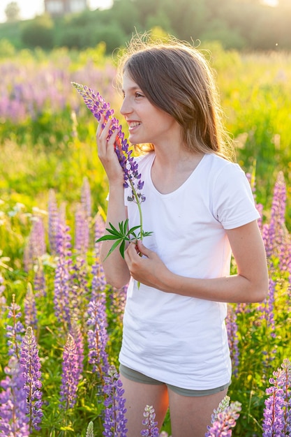 Счастливая девочка-подросток улыбается на открытом воздухе Красивая молодая женщина-подросток отдыхает на летнем поле с цветущими дикими цветами на зеленом фоне Бесплатный счастливый ребенок девочка-подросток концепция детства