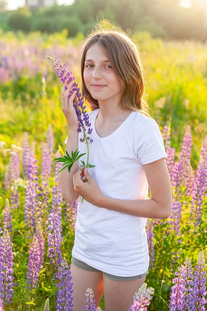 Adolescente felice sorridente all'aperto bella giovane donna adolescente che riposa sul campo estivo con fiori selvatici in fiore sfondo verde concetto di infanzia della ragazza dell'adolescente del bambino felice libero