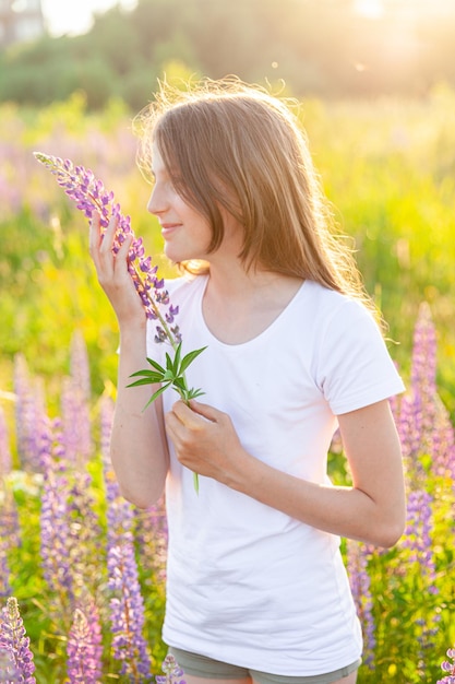 Happy teenage girl smiling outdoor beautiful young teen woman resting on summer field with blooming ...