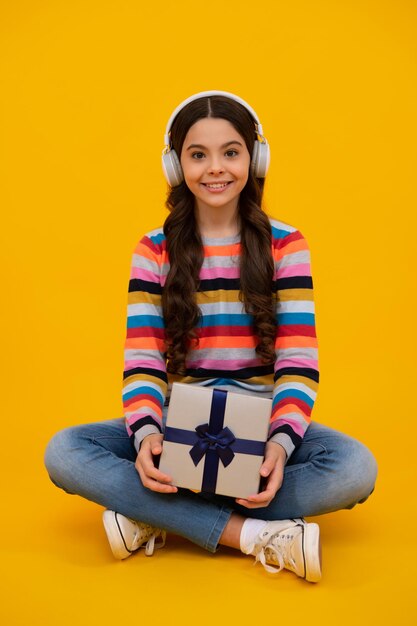 Happy teenage girl teenager child holding gift box on isolated yellow background gift for kids birthday christmas or new year present box smiling kids emotions