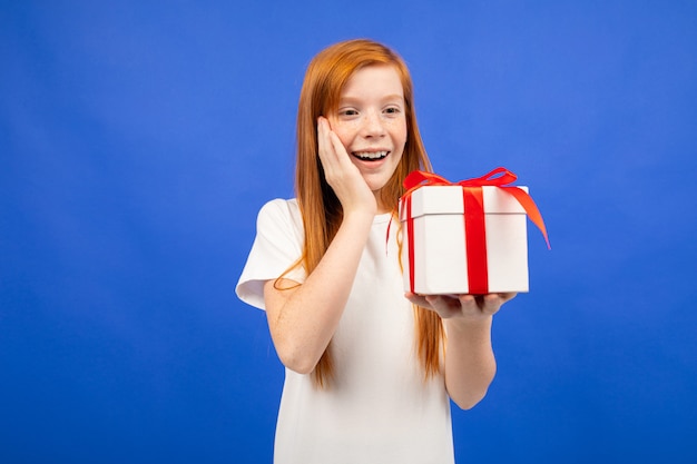 Happy teenage girl with red hair received a birthday present blue