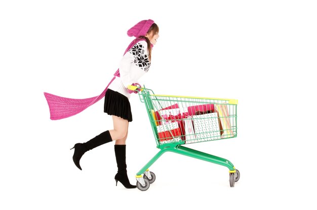 happy teenage girl with shopping cart over white