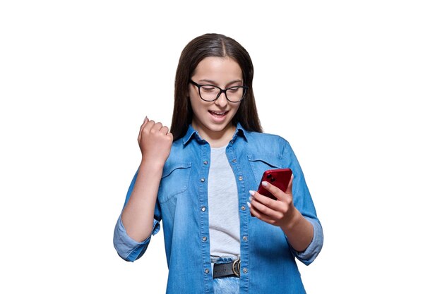 Happy teenage girl with smartphone in her hands emotion yes happiness success winner joy posing on white isolated background emotional cheerful female looking at phone raises fist up