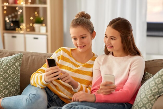 happy teenage girls with smartphones at home