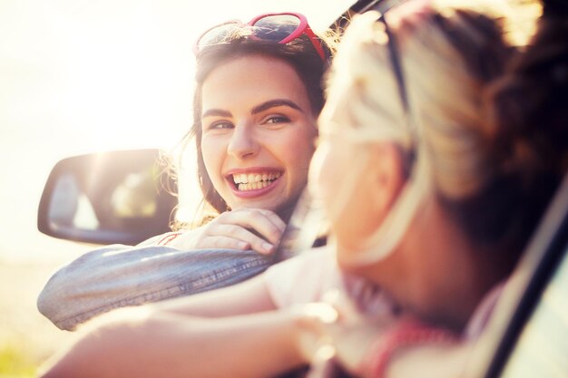 Photo happy teenage girls or women in car at seaside