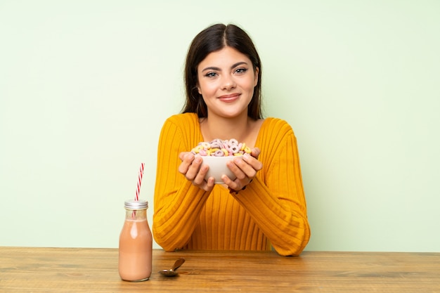 シリアルのボウルで朝食を食べて幸せなティーンエイジャーの女の子