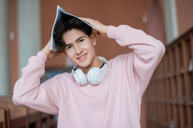 Happy teenager holding copybook over head while posing