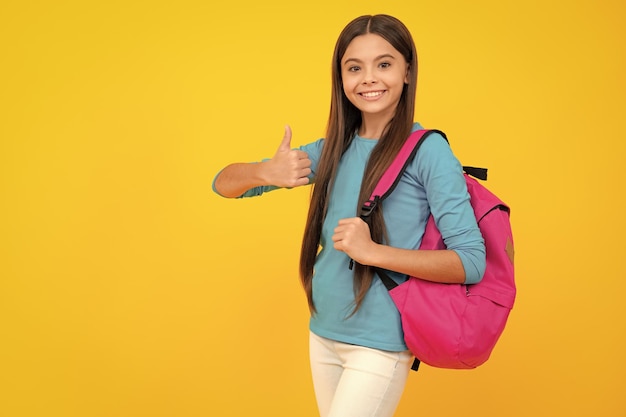 Happy teenager portrait Back to school Teenage school girl ready to learn School children on yellow isolated background Smiling girl