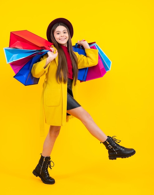 Happy teenager portrait Child girl hold shopping bag enjoying sale isolated on yellow background Run