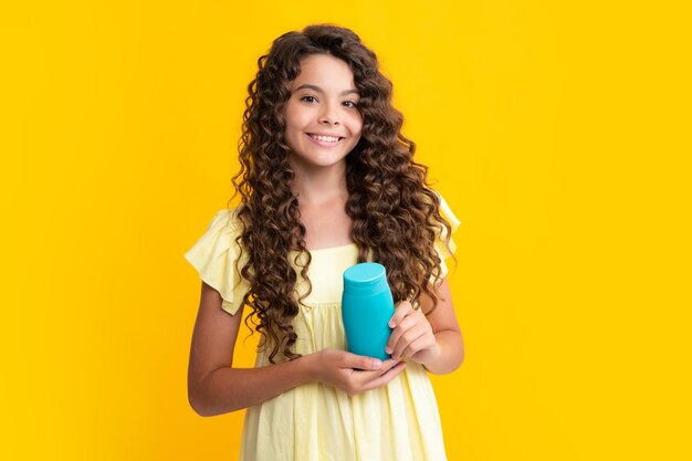 Happy teenager portrait of child girl with bottle shampoo conditioners or shower gel kids hair care hair cosmetic product shampoo bottle smiling girl