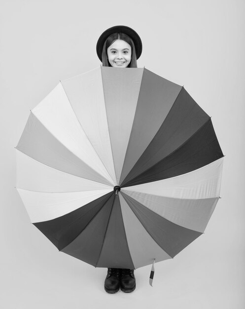 Happy teenager portrait child teenager girl with umbrella isolated on yellow studio background smiling girl