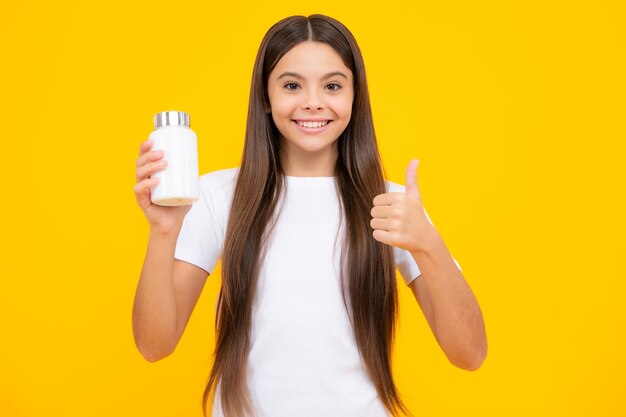 Happy teenager portrait Staying healthy Teenage girl holding vitamin pills on yellow isolated background Smiling girl