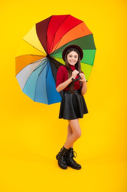 Happy teenager portrait Teen girl with umbrella in autumn weather isolated on yellow background Autumn kids clothes