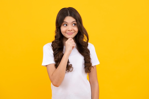 Happy teenager positive and smiling emotions of teen girl Smart nerdy school girl touching cheek and thinking against yellow background Child think and idea concept