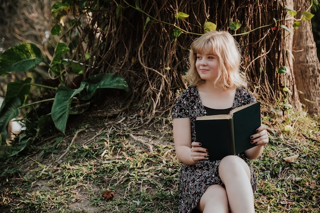 Happy teenager  reading book at park in summer.