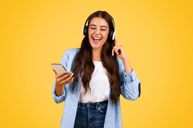 Foto studente adolescente felice che scrive su uno smartphone con le cuffie cantando una canzone
