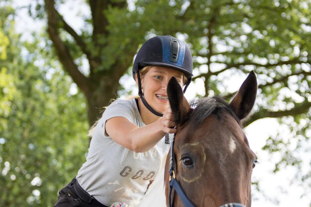 Foto un adolescente felice che tocca l'orecchio di un cavallo