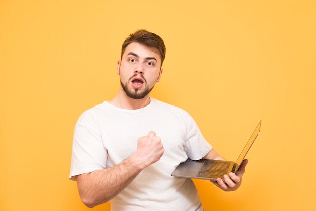 Happy teenager in a white T-shirt holds the laptop in his hands