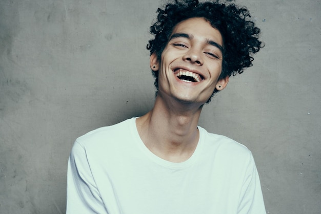 Happy teenager in white tshirt curly hair laughing smile beige background photography studio