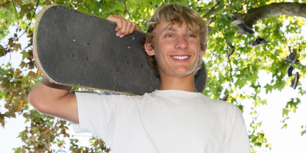 Photo happy teenager with a skateboard in his hand and shoulders