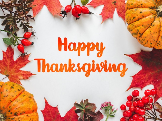 happy thanksgiving bright pumpkins tree leaves red berries and colorful flowers lying on an empty table closeup view from above congratulations for loved ones relatives friends and colleagues