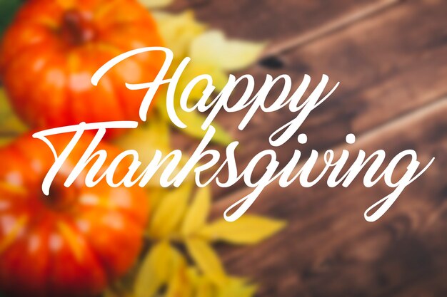 happy thanksgiving concept with orange pumpkins yellow leaves and cup of coffee on wooden