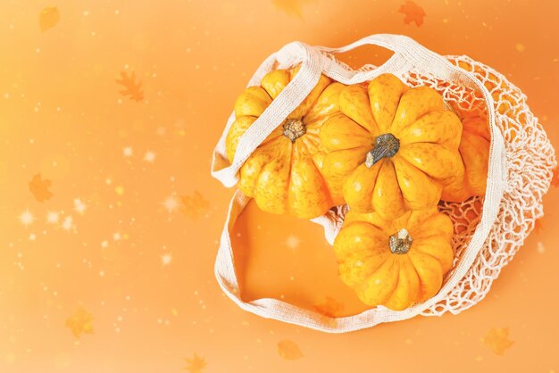 Foto happy thanksgivingvegetable fall food conceptautumn halloween pumpkinsdiverse varietà di zucche in sacchetto di tessuto a maglia su sfondo arancioneautumn conceptcopy spacecomposizione di zucche