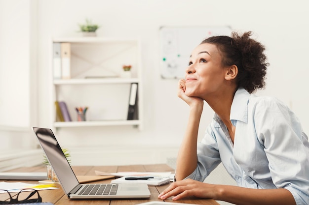 Happy thoughtful business woman working on laptop at office. Businesswoman sitting at her working place, copy space