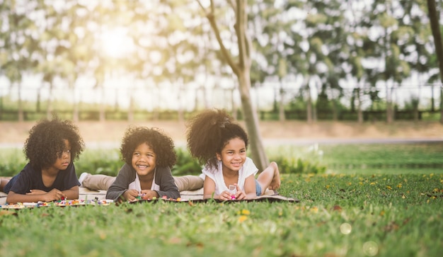 Foto tre piccoli amici felici che mettono sull'erba nel parco