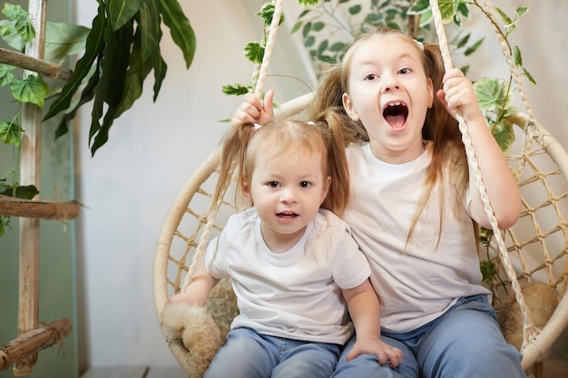 Happy time concept girls sisters in chair and having fun female preschooler and teenager playing