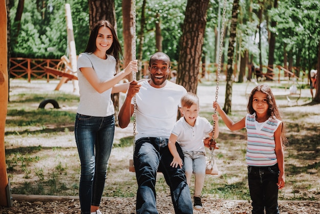 Happy time together mom dad and kids on swing