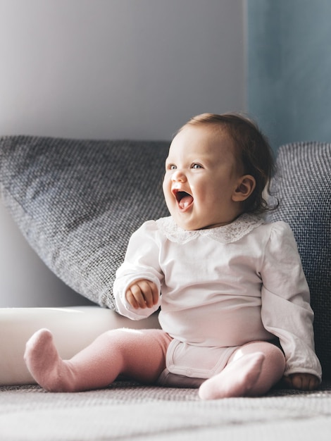 Happy toddler baby girl laughing on couch at home Childhood