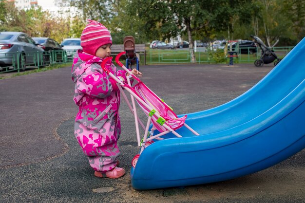 Ragazzo felice del bambino che gioca su una diapositiva in un parco giochi con tempo freddo