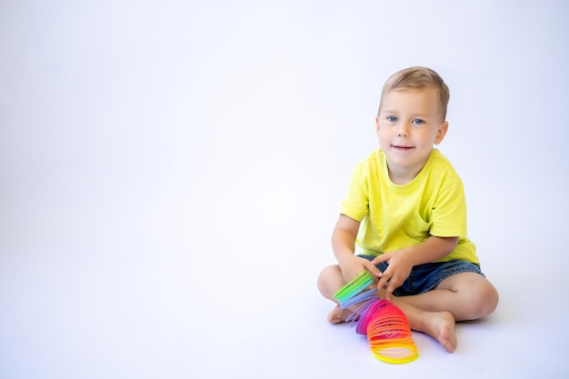 白い背景に明るいプラスチック製のおもちゃで遊んで幸せな幼児の男の子は、子供のための教育玩具を分離しました