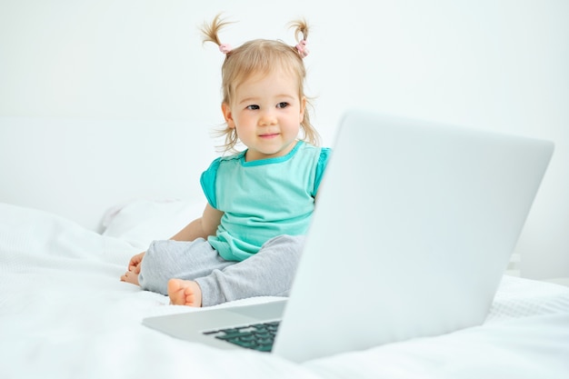 Happy toddler sits and looks at the laptop