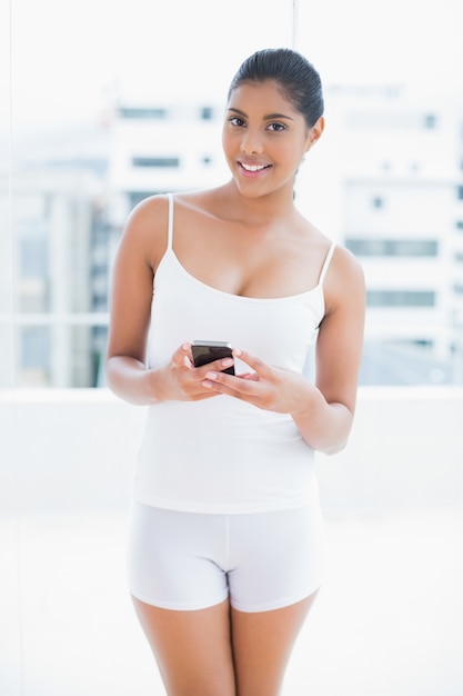 Happy toned brunette holding smartphone