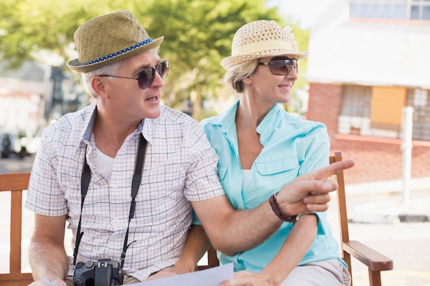 Happy tourist couple looking at map in the city