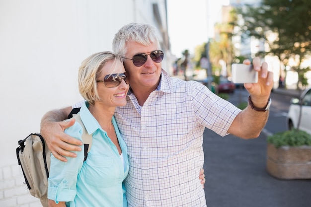 Happy tourist couple taking a selfie in the city