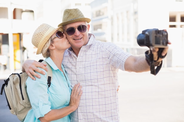 Foto coppie turistiche felici che prendono un selfie nella città