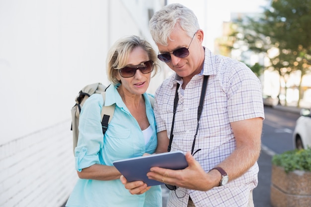 Happy tourist couple using tablet in the city