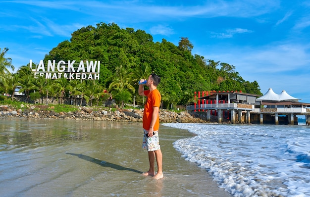 Ragazzo turistico felice sulla spiaggia centrale nell'isola tropicale di langkawi