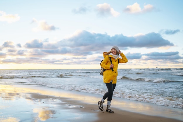 写真 夕暮れ時の海の風景を楽しむ黄色いジャケットを着た幸せな観光客旅行ライフスタイルアドベンチャー
