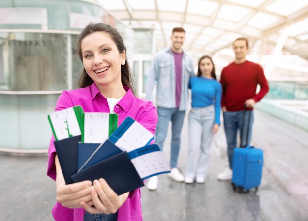 空港で友人と旅行するチケットを示す幸せな観光客の女性