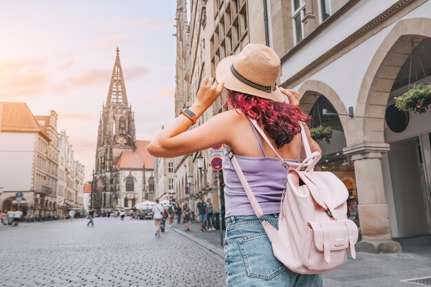 Foto felice donna turistica con zaino che visita la via prinzipalmarkt e ammira gli edifici dell'architettura della città vecchia a munster germania